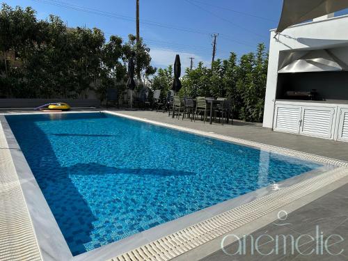 a swimming pool with blue water in front of a house at anemelie in Sotira