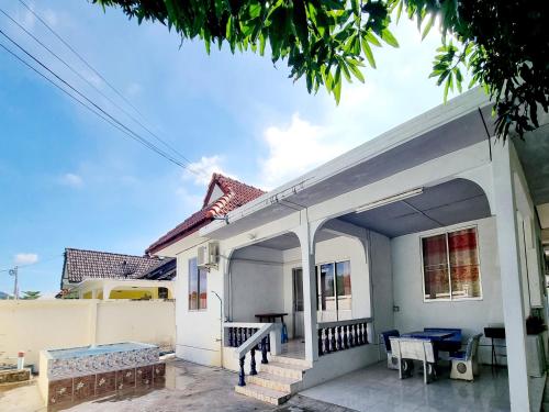 a white house with a patio and a table at Mae Rampung Beach House คาราโอเกะและสระเด็ก in Rayong