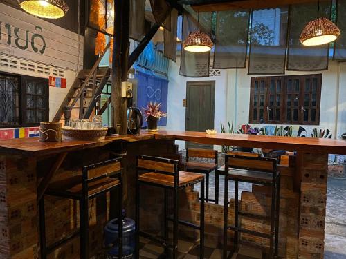 a bar with wooden tables and chairs in a room at Khonesavane Hostel in Luang Prabang