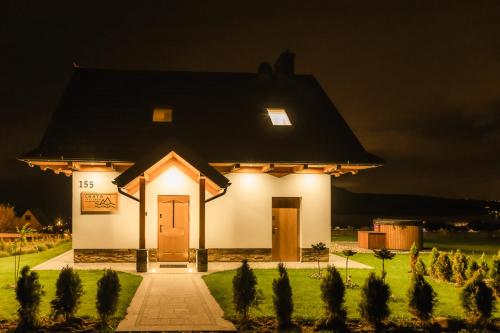 a small white house with a light on it at night at Chata Stylchyn in Kluszkowce