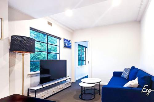 a living room with a blue couch and a tv at MCG Best Unit For Fireworks 1BR Sleeps3 in Melbourne