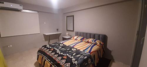 Un dormitorio con una cama con una manta. en DEPARTAMENTO EN PLENO CENTRO DE GUAYAQUIL, en Guayaquil