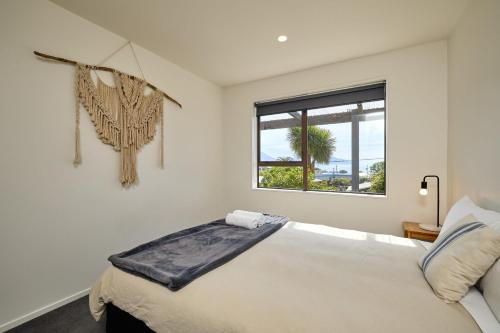 a white bedroom with a bed and a window at Hot Tub, Great Views, Close to Beach in Kaikoura