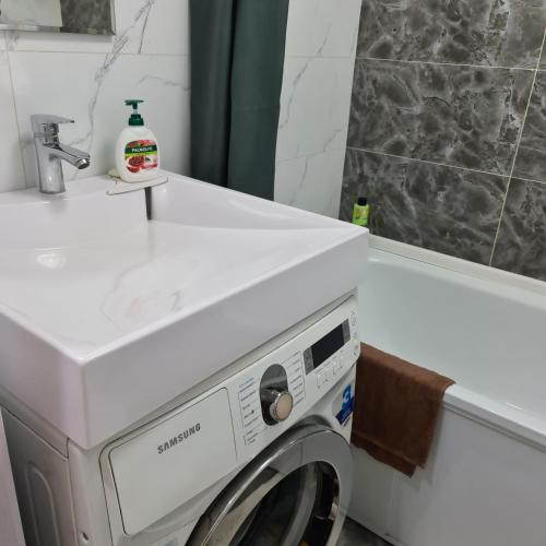una lavatrice in un bagno accanto a un lavandino di Дом77, проспект БухарЖырау a Karagandy