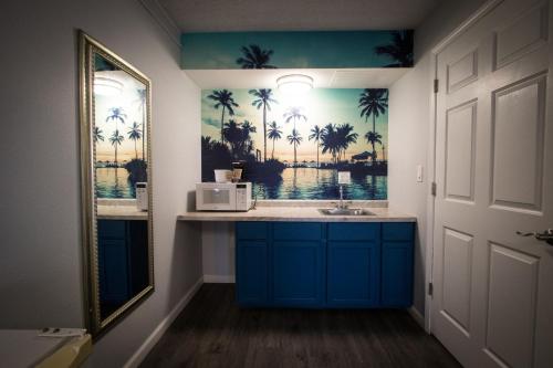 a bathroom with a sink and a mirror and palm trees at Envi Boutique Hotel Henderson-Evansville South in Henderson