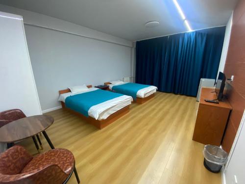 een kamer met 2 bedden en een tafel en een stoel bij Etuga Guesthouse, Close to Sukhbaatar Square in Ulaanbaatar
