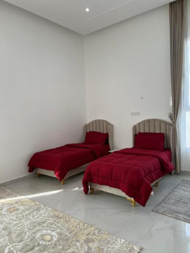 two beds in a white room with red sheets at Monsoon Chalet - شاليه المونسون in Junayz al Janūbī
