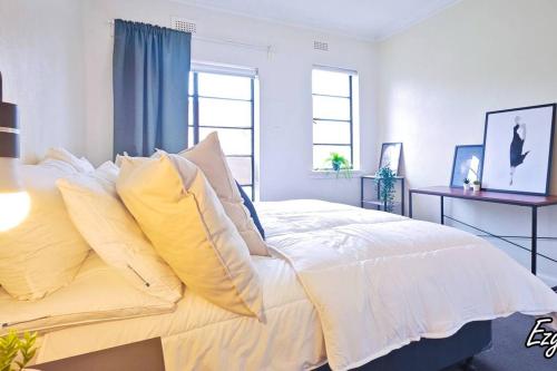 メルボルンにあるMCG 1BR Apartment For Familyの白いベッド(黄色い枕付)が備わるベッドルームです。