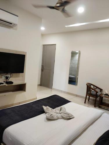 a bedroom with a large white bed with a ceiling fan at Hotel Hamilton in Zirakpur