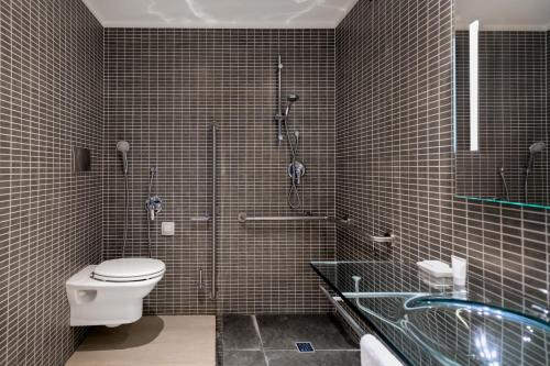 a bathroom with a toilet and a shower and a sink at AC Hotel by Marriott Pisa in Pisa