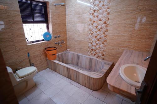 a bathroom with a tub and a toilet and a sink at Madaan Villas in New Delhi