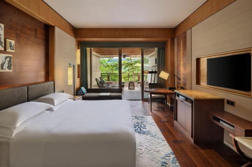 um quarto com uma cama grande e uma televisão de ecrã plano em Sheraton Grand Xishuangbanna Hotel em Jinghong