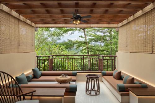 a screened in porch with couches and a ceiling fan at Sheraton Grand Xishuangbanna Hotel in Jinghong