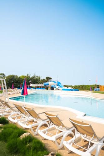 - une rangée de chaises longues dans une piscine dans l'établissement Camping Officiel Siblu Domaine de Dugny, à Onzain