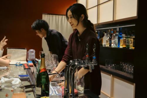a woman standing at a bar with a bottle of wine at 万雷ホテル in Tokyo