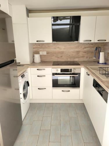 une cuisine avec des armoires blanches et une laveuse et une sécheuse dans l'établissement Le Nautile, résidence Les Corailleurs, duplex surplombant la mer, 6 pers, à Saint-Aygulf