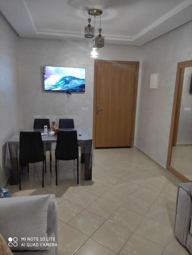 a dining room with a table and chairs and a television at Appartement moderne F3 tout neuf in Marrakech