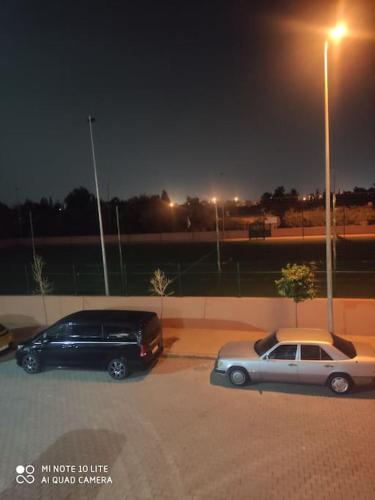 two cars parked in a parking lot at night at Appartement moderne F3 tout neuf in Marrakech