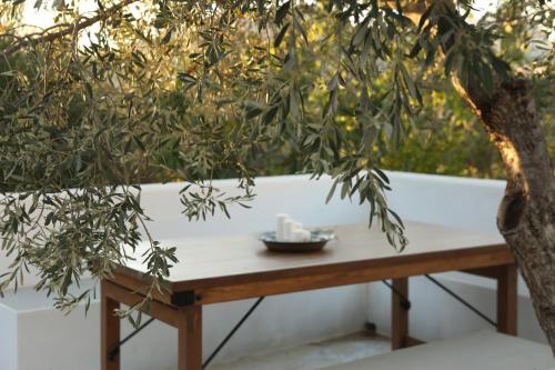 una mesa de madera bajo un árbol con un tazón. en Το σπιτάκι to spitaki Τhe little house, en Panormos Kalymnos