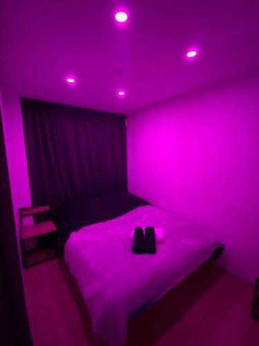 - une chambre avec des lumières roses sur un lit dans l'établissement LoVe 1, au Cap d'Agde