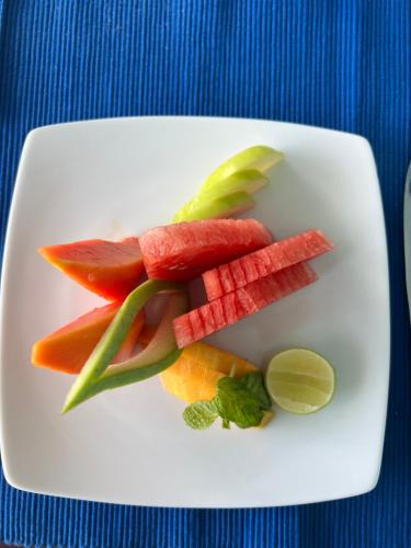 a white plate with fruits and vegetables on a table at Calypso Sunset in Iranawila