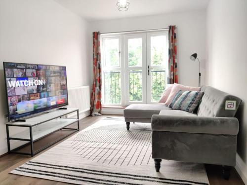 Elegant, Spacious 2bed in Crystal Palace, London في كريستال بالاس: غرفة معيشة مع أريكة وتلفزيون بشاشة مسطحة
