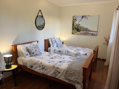 1 dormitorio con 2 camas y espejo en la pared en Palm beach Sydney, Modern home with water view en Palm Beach