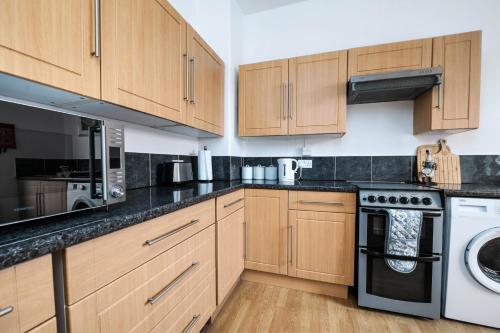 a kitchen with wooden cabinets and a washer and dryer at Spacious Apartment - Parking - Sleeps 5 in Great Coates