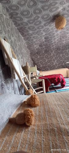 a bed with a teddy bear sitting on top of it at Serdrar Camp in Timganine