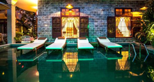 una piscina con bancos en un edificio en Ngan Phu Villa, en Hoi An