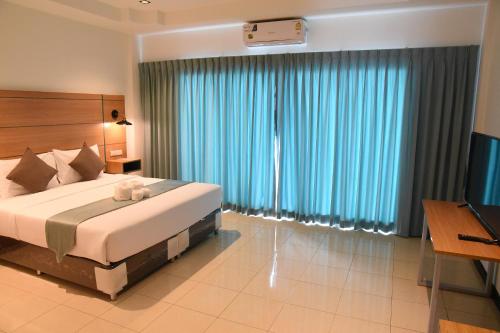 a bedroom with a large bed and a television at The Base Inn Pattaya in Pattaya Central