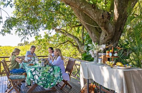 a group of people sitting at a table under a tree at Seaforth Country House in Ballito