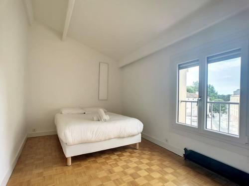 Habitación blanca con cama y ventana en Appartement la cité, en Périgueux