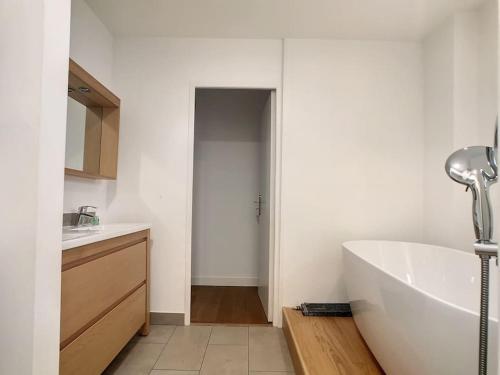 Baño blanco con bañera y lavamanos en Appartement la cité, en Périgueux