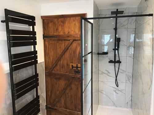 a shower with a wooden door in a bathroom at The Barn in Shirland