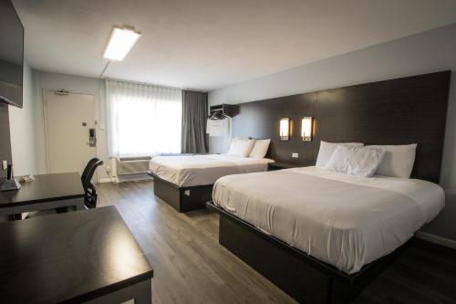 a hotel room with two beds and a desk at Envi Boutique Hotel Henderson-Evansville South in Henderson