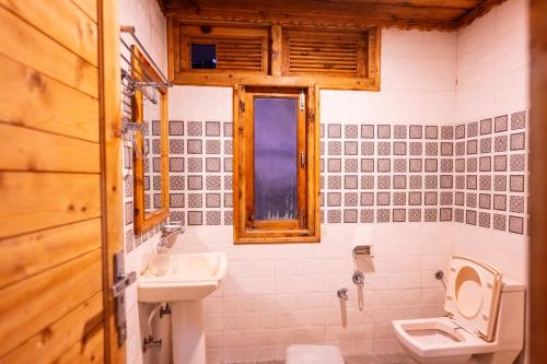 a bathroom with a sink and a toilet and a window at Norvin Homes in Shimla