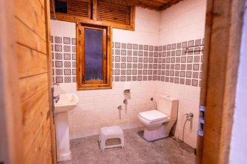 a bathroom with a toilet and a sink and a window at Norvin Homes in Shimla