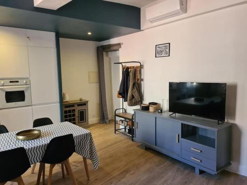 Il comprend un salon doté d'une télévision et d'une table avec des chaises. dans l'établissement Appartement T2 avec clim et wifi, à 50 m de la plage, à Collioure