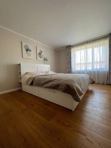 a white bedroom with a bed and a window at Ģimenes māja Jaunpilī in Jaunpils