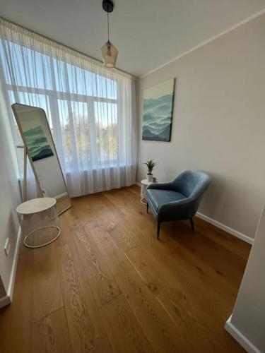 a living room with a blue chair and a large window at Ģimenes māja Jaunpilī in Jaunpils