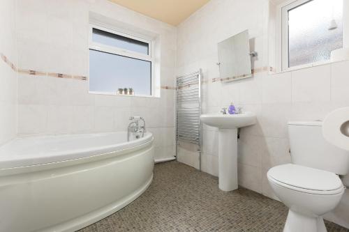 La salle de bains blanche est pourvue d'une baignoire, de toilettes et d'un lavabo. dans l'établissement Large 4 bed Coventry house Contractors Professionals Private parking Close to NEC, à Parkside
