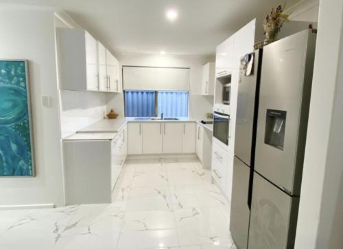 een keuken met witte kasten en een zwarte koelkast bij Bequia in Safety Bay