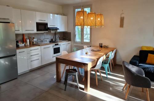 eine Küche und ein Esszimmer mit einem Holztisch in der Unterkunft Appart Magnolia Villeneuve les Avignon - Provence in Villeneuve-lès-Avignon
