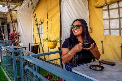 a woman sitting at a table holding a glass at Kalash Parkaze And Tent Inn in Pokhara