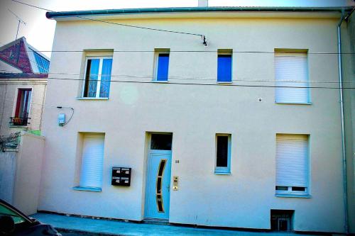 un edificio blanco con una puerta azul en una calle en Gheddachi en Gentilly