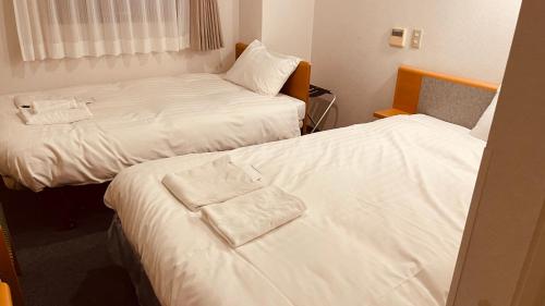 2 camas en una habitación de hotel con sábanas blancas en Hotel Nepal Inn Sauraha en Sauraha