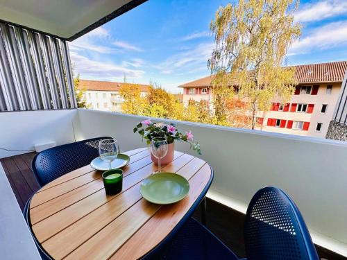 einen Holztisch mit zwei Gläsern und Blumen auf dem Balkon in der Unterkunft Modern City Studio with Balcony in Zürich