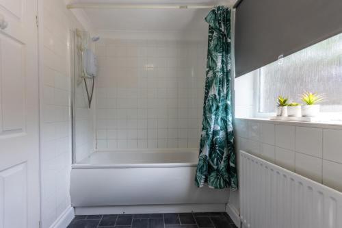 a bathroom with a tub and a shower curtain at Central 2bed Long Stays Parking Near Hospital in Southampton
