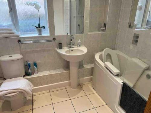 a bathroom with a sink and a toilet and a bath tub at A Lovely 2 bedroom ground floor flat, with parking in Walton-on-the-Naze